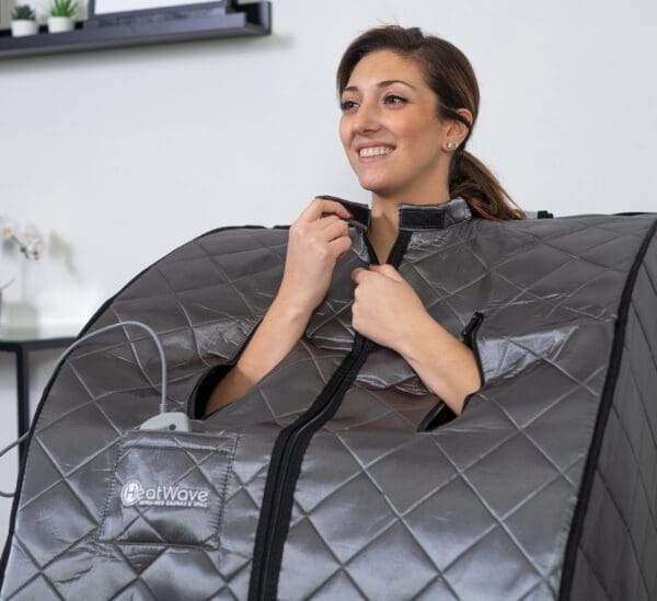 A woman is sitting in a Rejuvenator Portable Sauna.