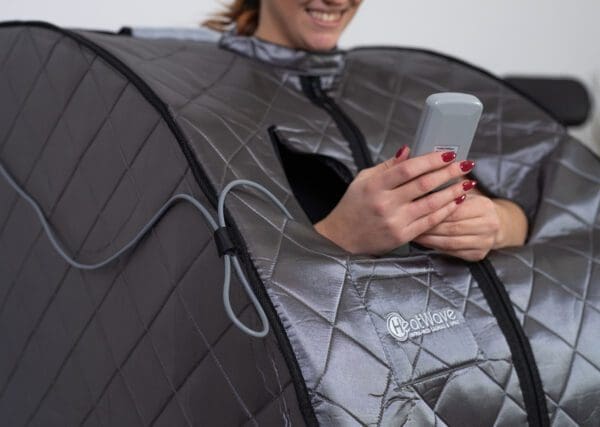 A woman using the Rejuvenator Portable Sauna while sitting in an infrared sauna.