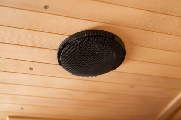 A Sirona 3-Person Hemlock Infrared Sauna with 8 Carbon Heaters on the ceiling of a wooden room.