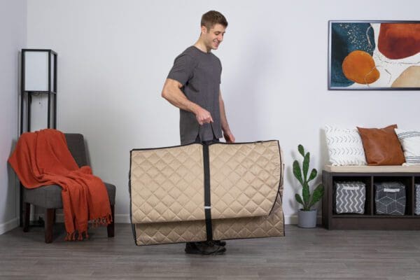 A man carrying a Valerian Portable Sauna in a living room.