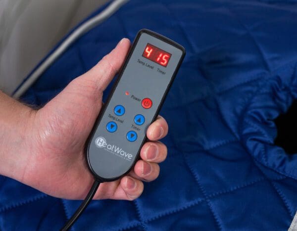 A person holding a Liberty Portable Sauna over a bed.