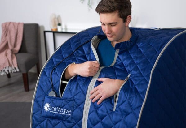 A man is sitting in a Liberty Portable Sauna.